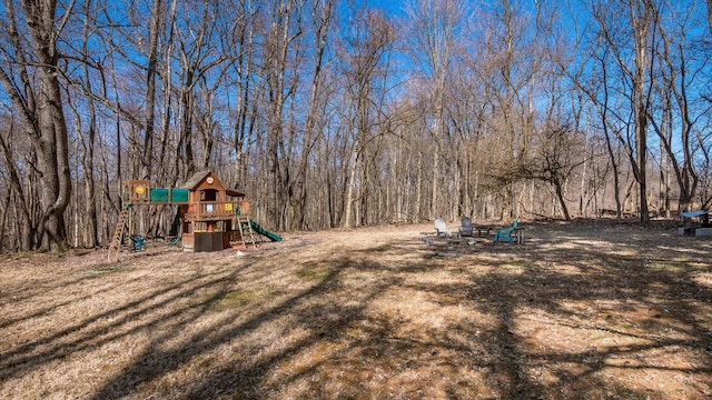 view of yard with a playground and a forest view