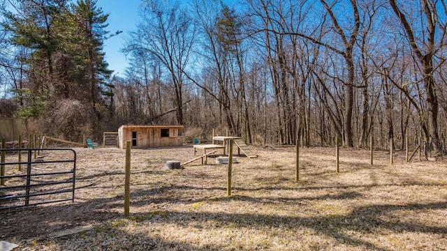 view of yard with an outbuilding, a view of trees, fence, and a gate