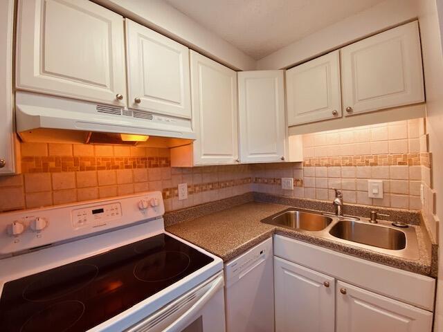 kitchen with under cabinet range hood, white appliances, white cabinets, and a sink