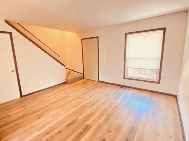 spare room featuring stairs and light wood-type flooring