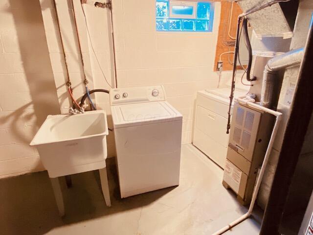 laundry area featuring laundry area, washer and dryer, concrete block wall, and a sink