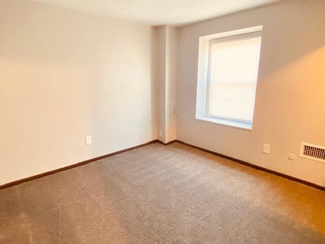 spare room featuring carpet flooring, visible vents, and baseboards