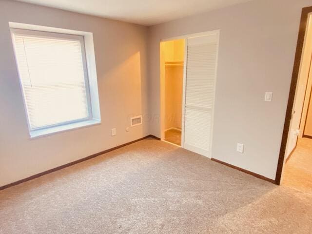 unfurnished bedroom with a closet, visible vents, carpet flooring, and baseboards