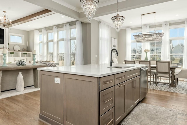 kitchen featuring gray cabinetry, a sink, light wood-style floors, stainless steel dishwasher, and a chandelier