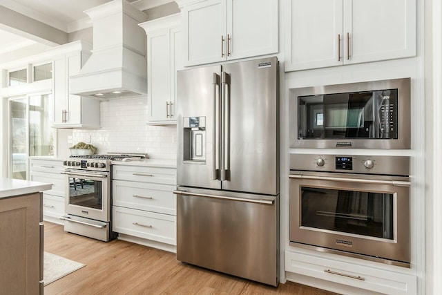 kitchen with custom exhaust hood, light wood-style flooring, stainless steel appliances, and light countertops