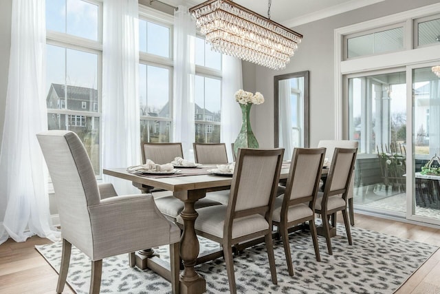 dining area featuring an inviting chandelier, light wood-style flooring, and ornamental molding