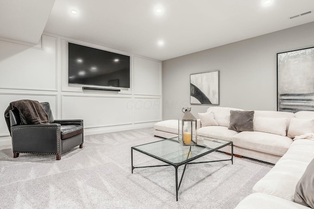 carpeted living room with a decorative wall, recessed lighting, and visible vents