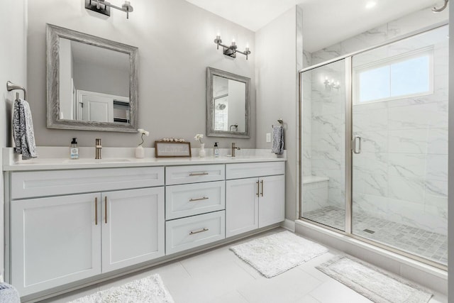 full bath with a marble finish shower, double vanity, and a sink