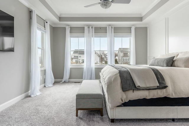 carpeted bedroom with a raised ceiling, baseboards, and ornamental molding