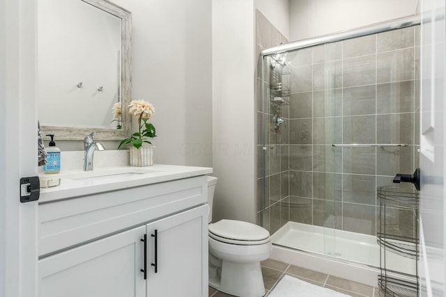 bathroom featuring tile patterned floors, vanity, toilet, and a shower stall