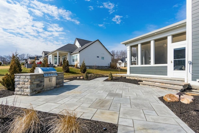 view of patio / terrace featuring grilling area, an outdoor kitchen, and a sunroom