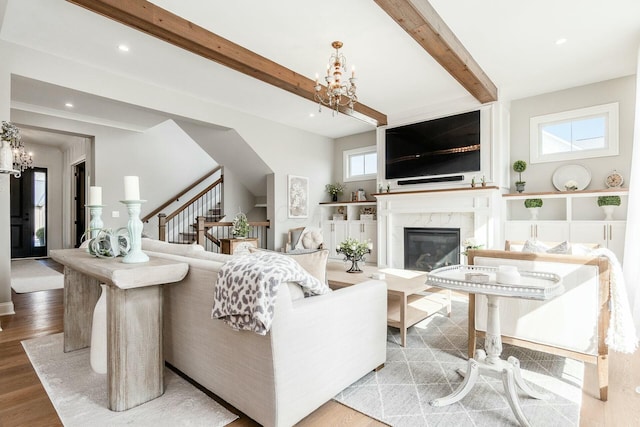 living area with stairs, beam ceiling, recessed lighting, wood finished floors, and a notable chandelier