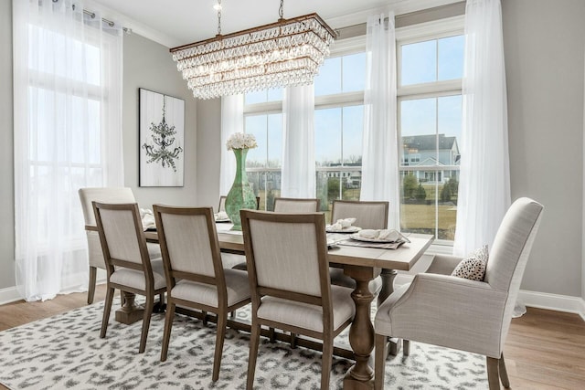 dining space featuring a chandelier, ornamental molding, baseboards, and wood finished floors