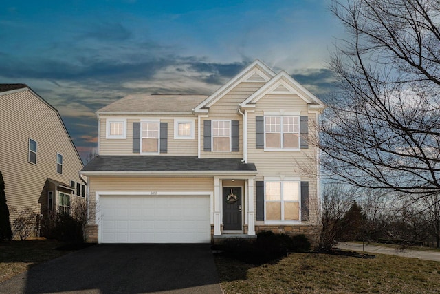 view of front facade featuring aphalt driveway, stone siding, and an attached garage