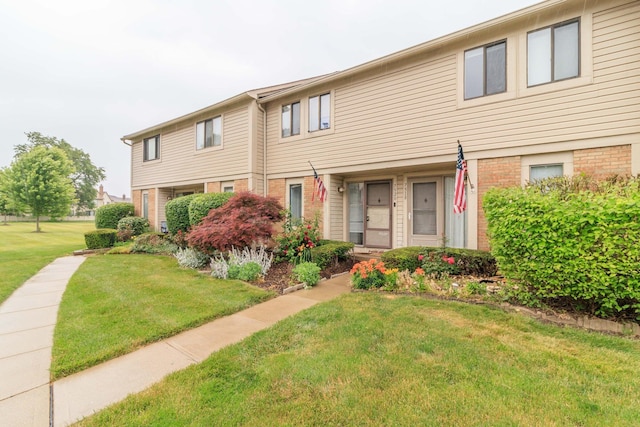 multi unit property with brick siding and a front lawn