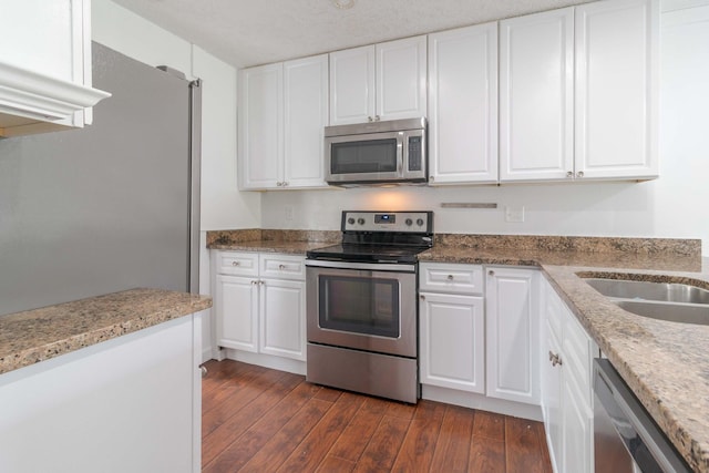 kitchen with stainless steel appliances, dark wood finished floors, and white cabinets