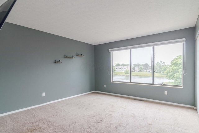 carpeted empty room with visible vents, a textured ceiling, and baseboards