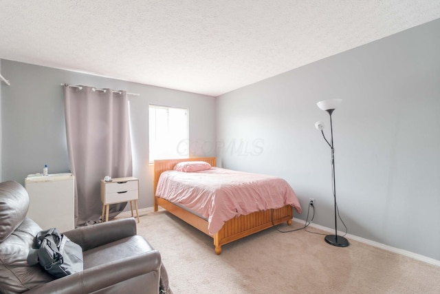 bedroom with light carpet, a textured ceiling, and baseboards