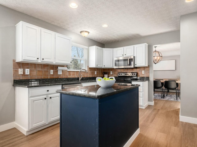 kitchen with tasteful backsplash, appliances with stainless steel finishes, white cabinetry, and light wood-type flooring