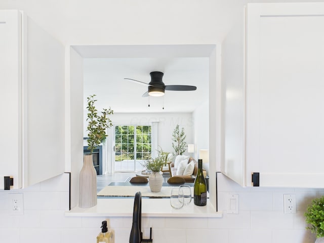 interior details with tasteful backsplash, white cabinetry, and ceiling fan