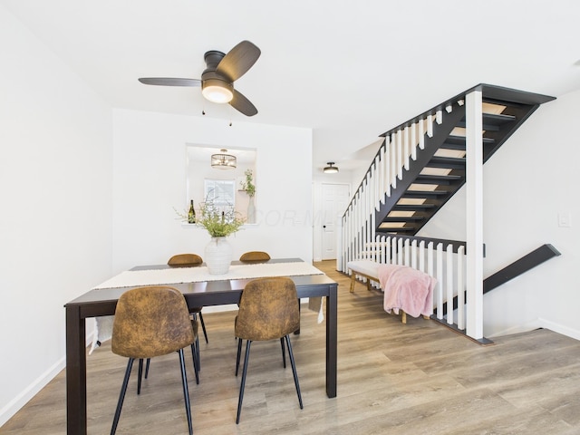 dining space featuring baseboards, a ceiling fan, wood finished floors, and stairs