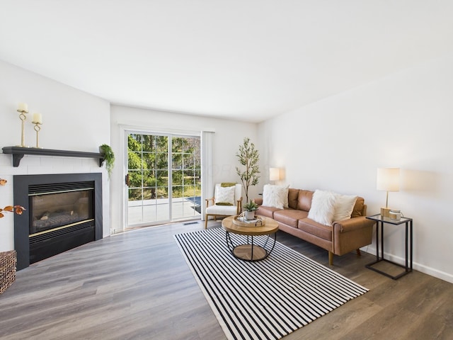 living room with a glass covered fireplace, baseboards, and wood finished floors