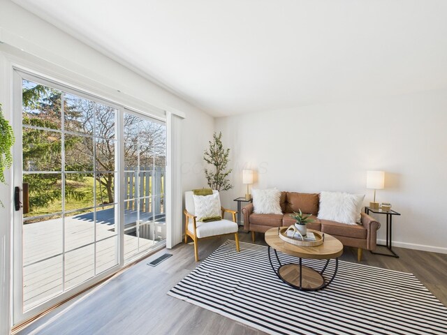 living area featuring plenty of natural light, wood finished floors, visible vents, and baseboards