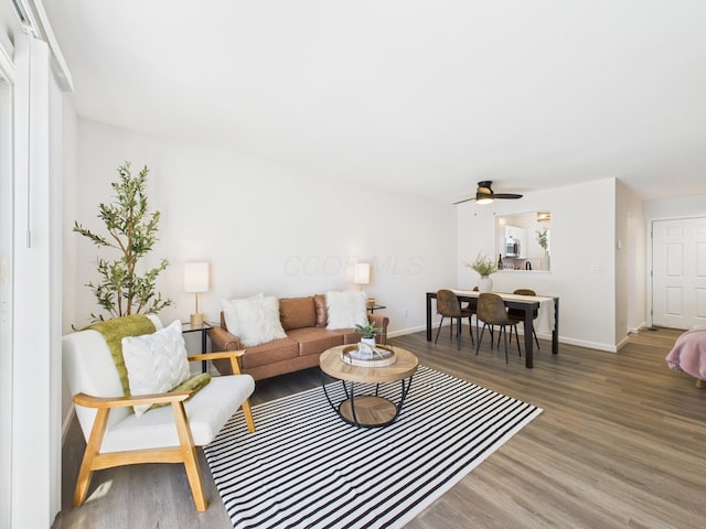 living room with a ceiling fan, wood finished floors, and baseboards