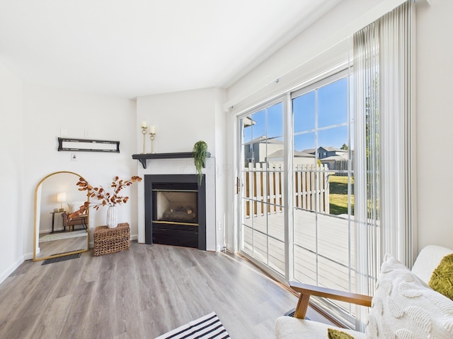 living area featuring a glass covered fireplace, baseboards, and wood finished floors