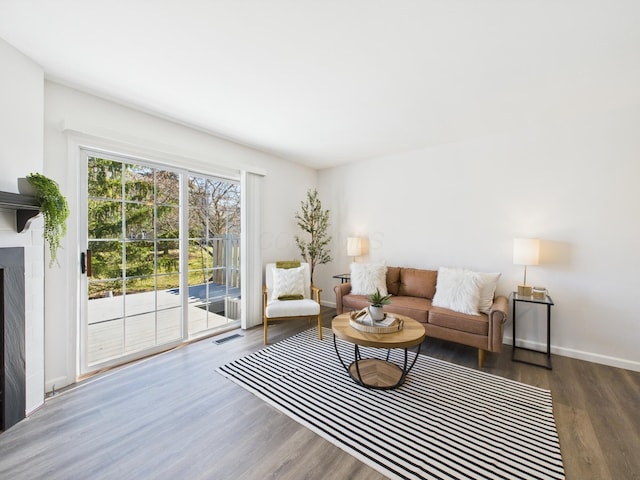 living room featuring visible vents, baseboards, wood finished floors, and a fireplace