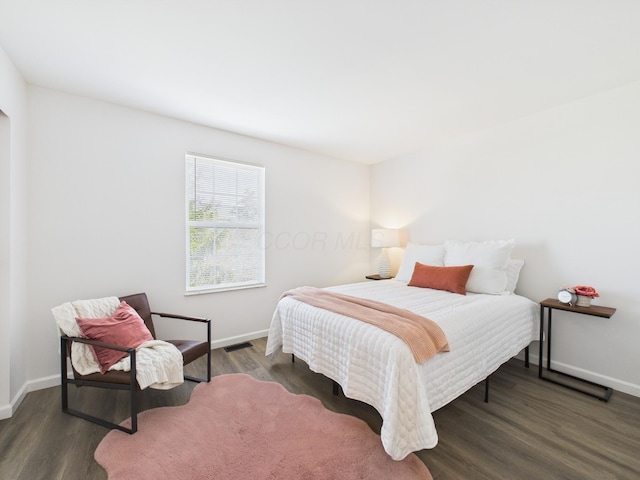 bedroom featuring visible vents, baseboards, and wood finished floors