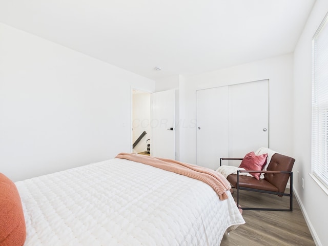 bedroom with wood finished floors, a closet, and baseboards