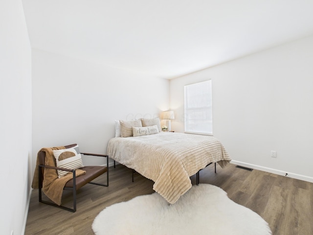 bedroom featuring visible vents, baseboards, and wood finished floors