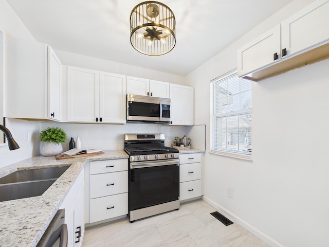 kitchen featuring visible vents, a sink, tasteful backsplash, stainless steel appliances, and white cabinets