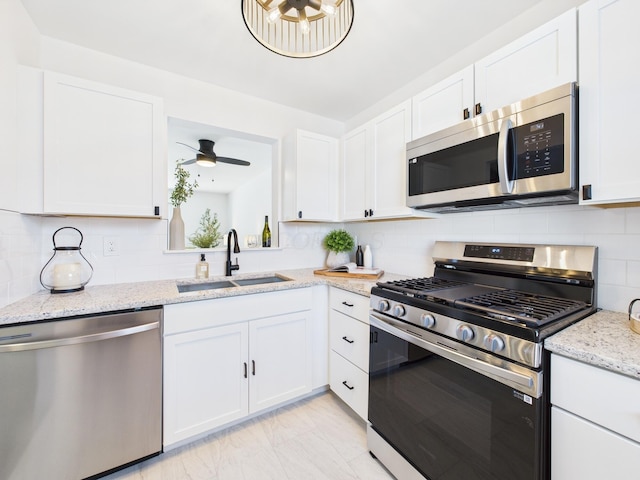 kitchen featuring tasteful backsplash, ceiling fan, appliances with stainless steel finishes, white cabinets, and a sink