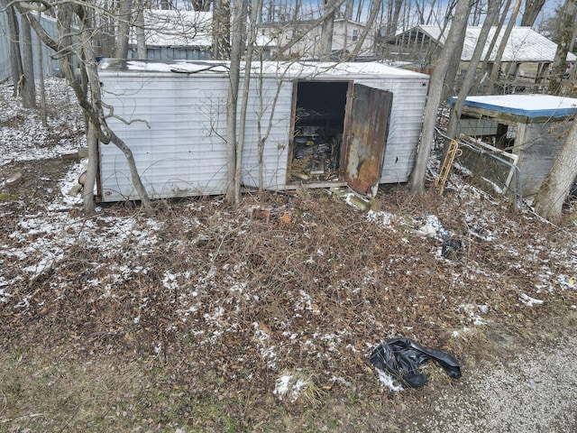 snow covered structure with a storage shed and an outdoor structure