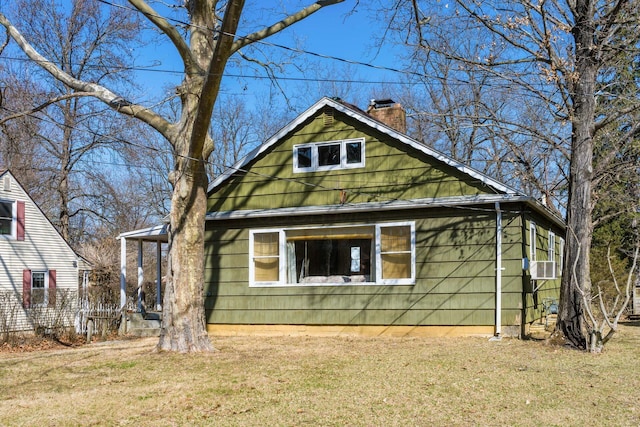 exterior space with cooling unit, a chimney, and a front yard