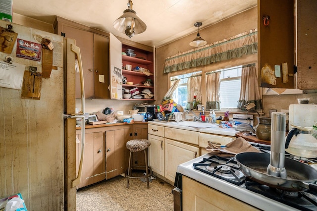 kitchen with a sink, freestanding refrigerator, light countertops, light floors, and hanging light fixtures