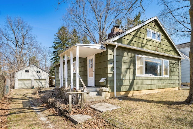 view of front of property with a garage, driveway, an outbuilding, and a chimney