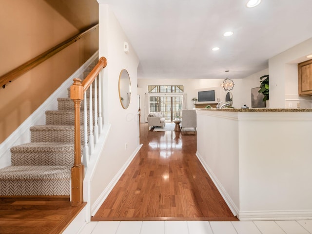 entrance foyer featuring baseboards, stairway, recessed lighting, wood finished floors, and a notable chandelier