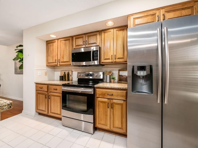 kitchen with decorative backsplash, light stone countertops, baseboards, and stainless steel appliances