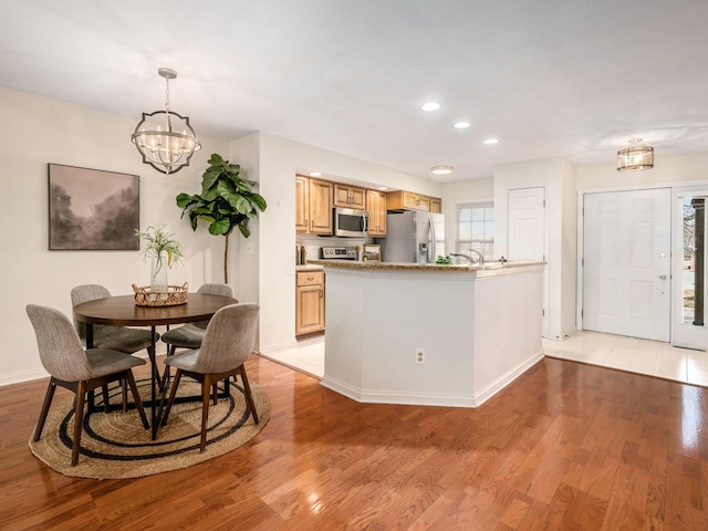 kitchen featuring decorative light fixtures, recessed lighting, appliances with stainless steel finishes, light wood finished floors, and a chandelier