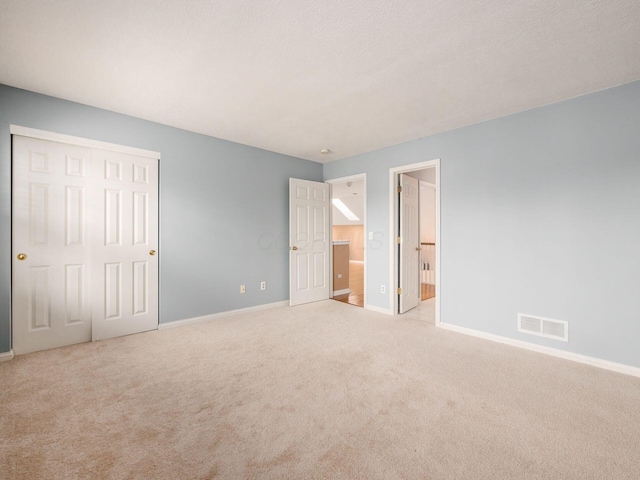 unfurnished bedroom featuring visible vents, a closet, carpet floors, connected bathroom, and baseboards