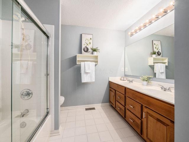 bathroom featuring double vanity, combined bath / shower with glass door, a textured ceiling, and a sink