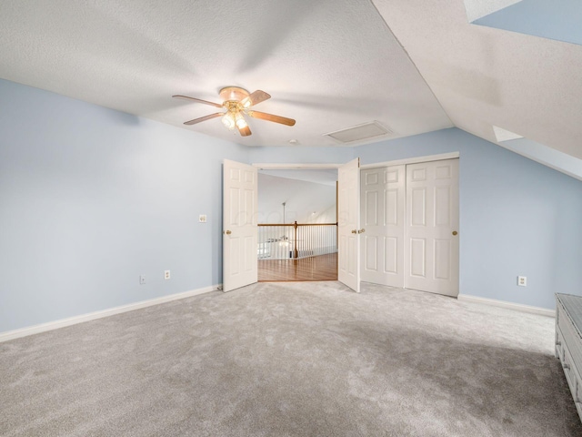 unfurnished bedroom with a textured ceiling, lofted ceiling, and carpet