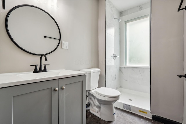 bathroom with toilet, vanity, and a tile shower