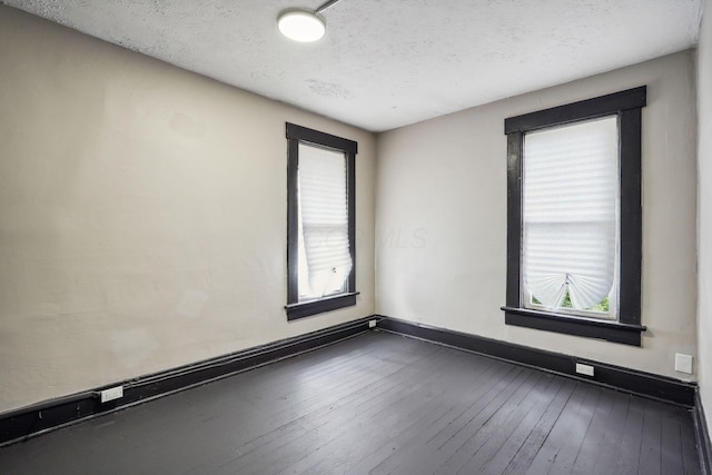 spare room featuring dark wood-style floors, baseboards, and a textured ceiling