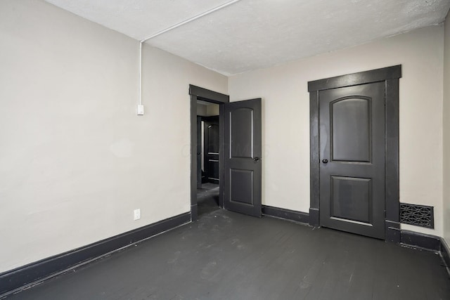 unfurnished bedroom with visible vents, baseboards, and dark wood-style flooring