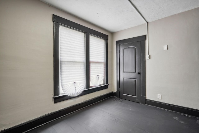 spare room featuring visible vents, a textured ceiling, baseboards, and wood finished floors