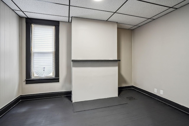 interior space featuring a drop ceiling, baseboards, visible vents, and dark wood finished floors